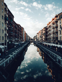 Canal amidst buildings in city against sky