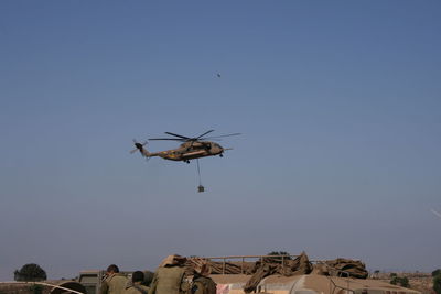 Low angle view of helicopter flying against clear blue sky