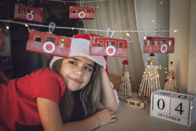 Cute girl looking away while sitting by christmas decoration