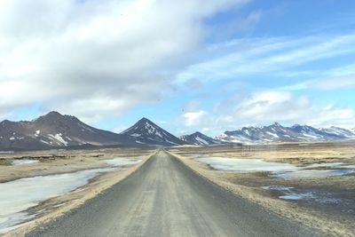 Road by snowcapped mountains against sky