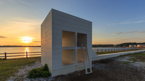 Built structure on beach against sky during sunset