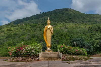 Statue against trees and plants against sky