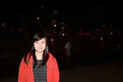 Portrait of smiling young woman standing at night