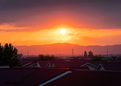 Houses and buildings against sky during sunset