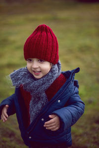 Child boy in knitted red hat and scarf in autumn on the street