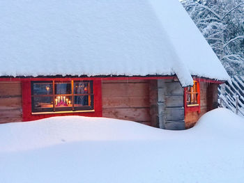 Built structure by snow covered house against sky during winter