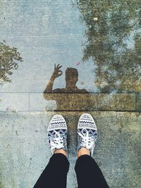 Low section of person standing by puddle on footpath