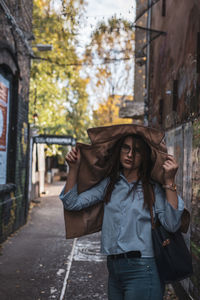 Portrait of young woman wearing jacket while standing at alley