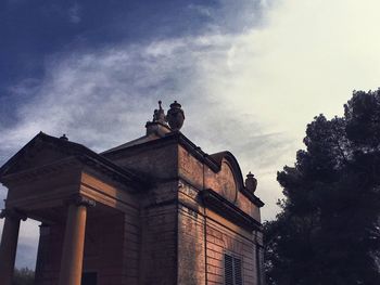 Low angle view of bird perching on statue against sky