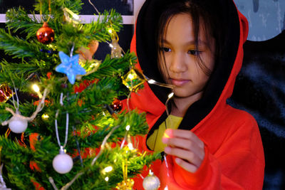 Cute girl decorating christmas tree at home