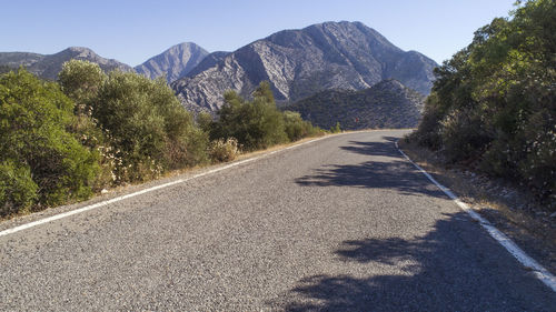 Road amidst trees and mountains against sky