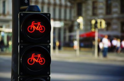 Close-up of illuminated bicycle sign on road signal by city street