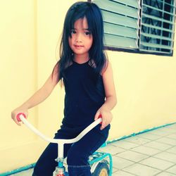 Cute girl riding bicycle outside house