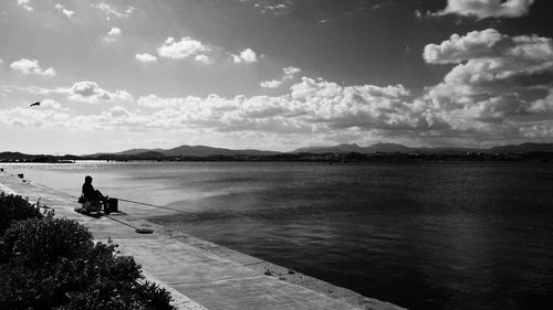 Silhouette man on pier fishing in river