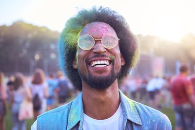 Young man with multi colored powder paint against sky