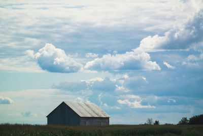 Houses on field against cloudy sky