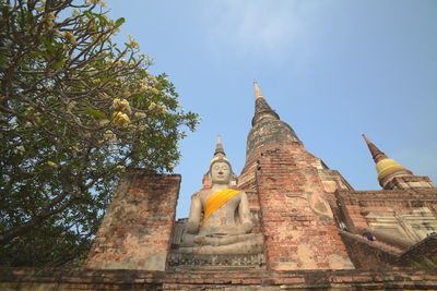 Low angle view of statue amidst buildings against sky