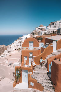 High angle view of townscape by sea against clear blue sky