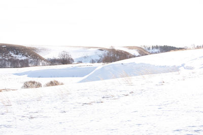 Snow covered landscape against clear sky
