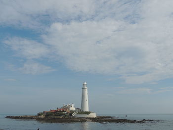 Lighthouse by sea against sky