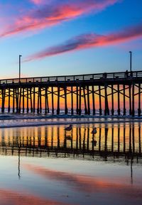 Silhouette bridge over river against sky during sunset