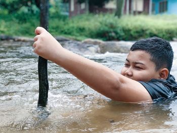 Boy catching fish while swimming in river