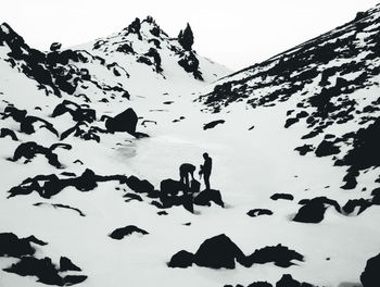 People on snowcapped mountain against sky