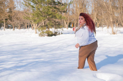 Young woman standing on snow covered field