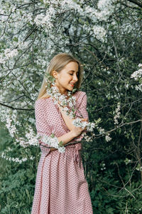 Blonde girl on a spring walk in the garden with cherry blossoms. female portrait, close-up. 