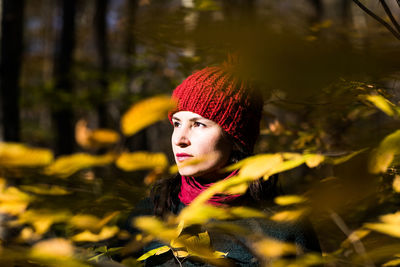 Young woman looking away amidst leaves