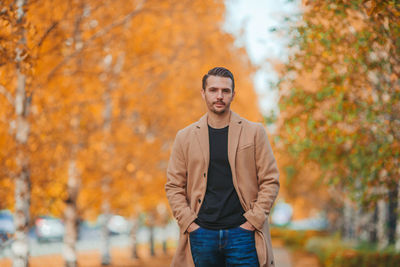 Portrait of young man standing against trees during autumn