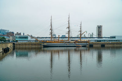 Boats moored at harbor against sky