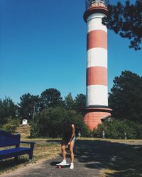 Woman with skateboard standing against lighthouse