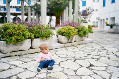 Full length of boy sitting on footpath