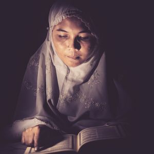 Woman reading quran in darkroom