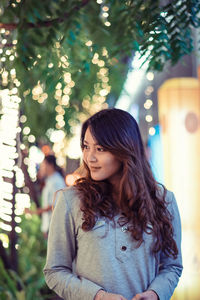 Close-up of young woman amidst illuminated lights