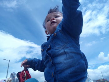 Low angle view of girl standing against sky