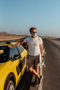 Full length of man standing by car against clear sky