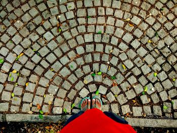 Low section of woman standing on cobblestone