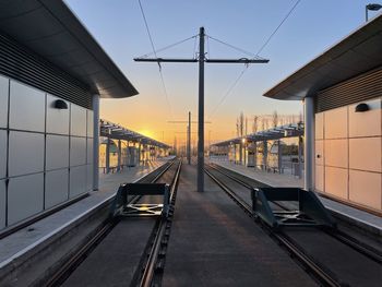 Railroad tracks amidst buildings against sky during sunset