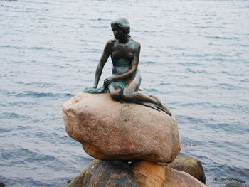 Statue of man sitting on sea