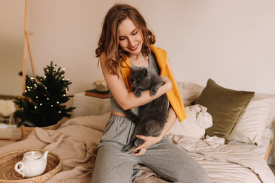 Portrait of young woman using mobile phone while sitting on bed at home