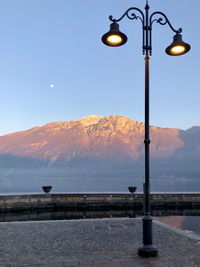 Street lights by mountains against sky