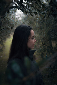 Side view of woman looking away in forest