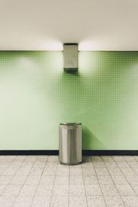 Garbage bin against green wall