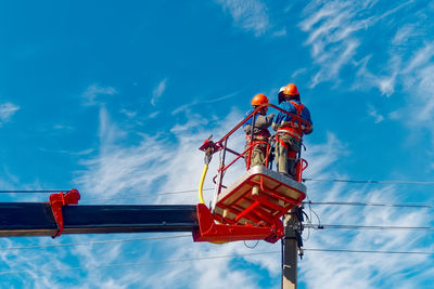 Low angle view of man climbing on roof against sky