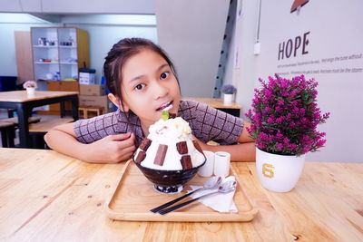 Portrait of young woman having food on table