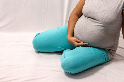 Midsection of woman sitting against wall