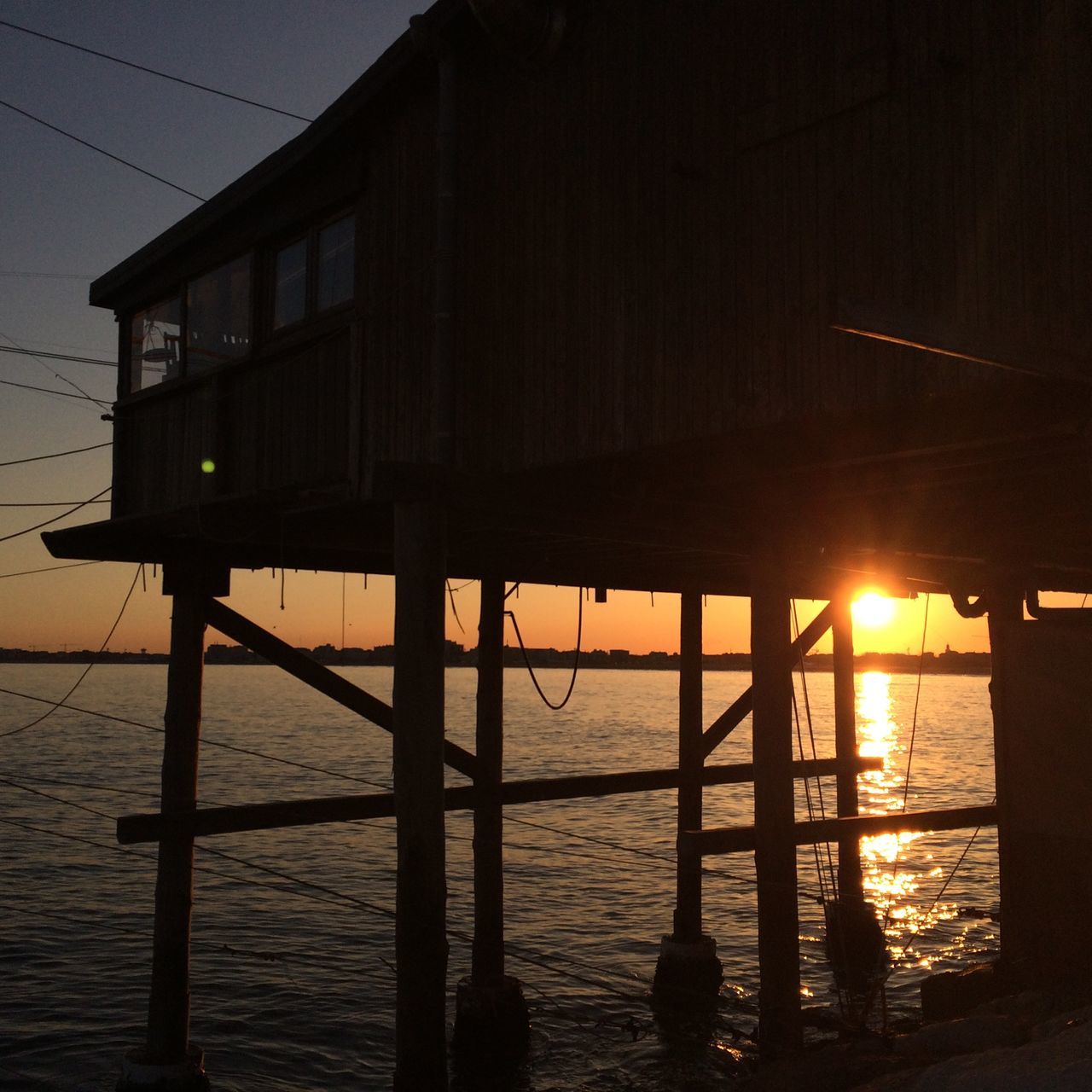 water, sunset, sea, built structure, reflection, illuminated, architecture, sky, tranquility, night, sun, beach, nature, silhouette, tranquil scene, scenics, outdoors, dusk, pier, no people