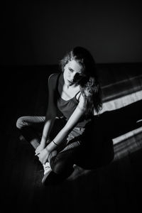 Young woman sitting against wall